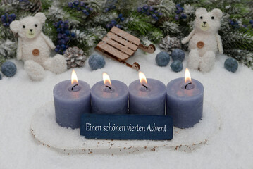 Vierter Advent: Dekoration mit vier blauen Adventskerzen, Weihnachtskugeln und Tedybär im Schnee.
