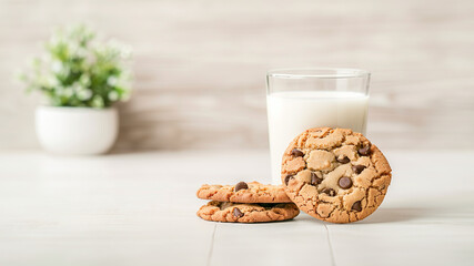 On a table sits a delicious glass of milk alongside chocolate chip cookies
