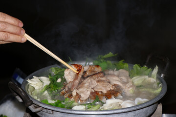 Women's hands are using chopsticks to grilled pork , Thai Barbecue Buffet with smoke