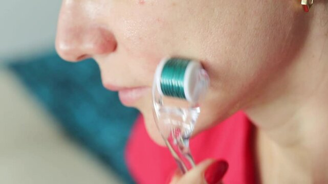 Slow motion footage of the woman using micro needle skin care derma roller on her face and neck, applying collagen. Cosmetics