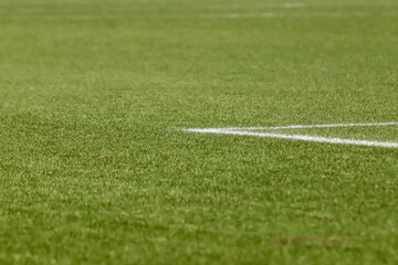 Football field with synthetic grass, with an angle below, highlighting the green of the lawn and some white lines.