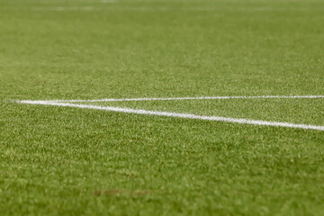 Obraz premium Football field with synthetic grass, with an angle below, highlighting the green of the lawn and some white lines.