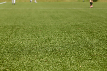 Football pitch with synthetic grass, with white lines on the lower two thirds and an athlete's feathers.
