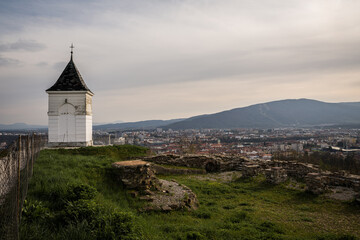 A panoramic view of Maribor, Slovenia, captured from Pyramid Hill (Piramida) during a serene spring afternoon, showcasing the city's red rooftops, sprawling streets, and surrounding landscape