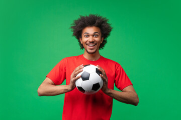 Studio portrait of a young casually dressed African American football fan man with soccer ball in hands smiling being happy to support favorite team