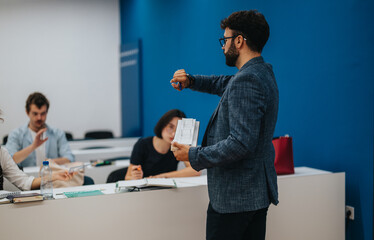 A professor assists his students in a lively classroom setting. The focus is on interaction, learning, and academic engagement as students work on tasks with the professor's guidance and support.