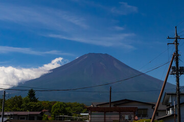 This is a beautiful image of Mount Fuji stretching up into the clear blue sky. White clouds can be...