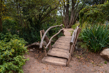 Small wooden bridge made with tree trunks crossing a creek inside a forest