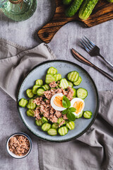 Keto salad with tuna, cucumber, egg and basil in a bowl on the table top and vertical view