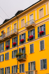 facade of the Italian yellow apartment building with pink flowers on the windows