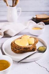 Morning sandwiches on grain bread with honey butter on a plate on the table vertical view