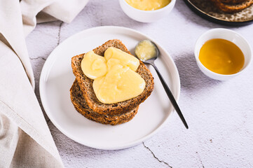 Delicious toasts with honey butter on a plate on the table