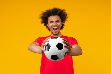 Studio shot of euphoric soccer supporter african american young man wearing basic red t-shirt...
