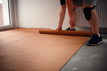 Man rolling out cork underlayment for flooring installation