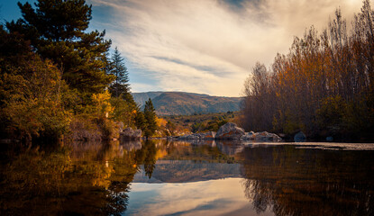 Mountain lake view with trees surrounding the calm water mirror at sunset in San Clemente in Cordoba, Argentina