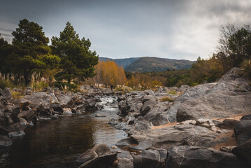 Mountain river view with trees surrounding the water while a man is fishing at San Clemente in Cordoba, Argentina