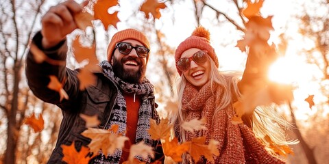 Fototapeta premium couple throwing autumn leaves, walking in a park, and having fun 