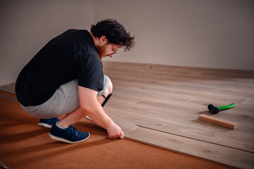 Man Installing Laminate Flooring with Tools