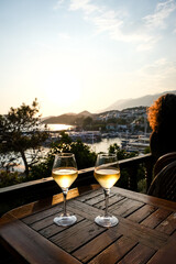 Drinking white wine in the bar or marine by the Mediterranean Sea at golden hour or sunset. Two glasses of white wine on the table