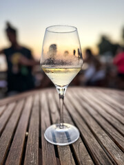 Glass of white wine on a table during sunset time. Golden hour, summer evening at open air bar.