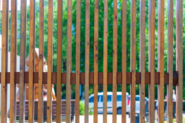 Obraz premium A wooden fence with a car in the background. The fence is brown and has a rustic feel to it. The car is parked on the street and is a silver color. The scene has a peaceful and calm atmosphere