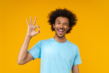 Portrait of young happy smiling African American man posing in studio over bright colored orange...