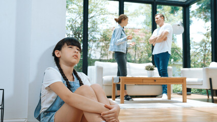 Stressed and unhappy young girl huddle in corner, cover her ears blocking sound of her parent...