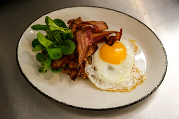 Lunch time. Open toast with avocado, crispy bacon and fried egg on a white ceramic plate. Delicious food.
