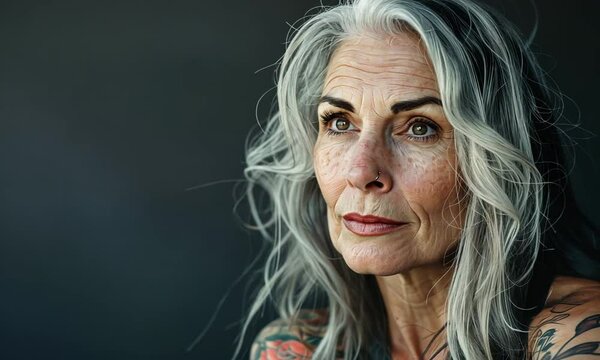 An enchanting elder woman with striking silver hair and intricate tattoos gazes thoughtfully into the distance, embodying a narrative of resilience and grace