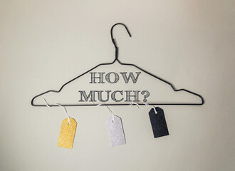 A clothes hanger with tags hanging from it that say How much? in black letters