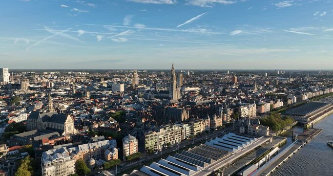 Cathedral along the Schelde river in Antwerp, Belgium. Aerial drone video at sunset, golden hour.