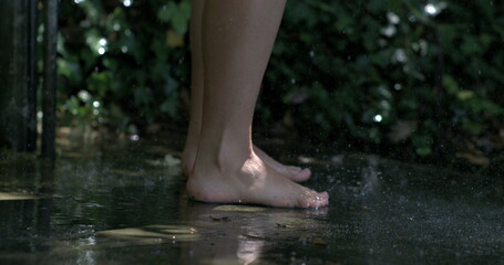 Bare feet on wet ground with water splashing around, slow-motion capture highlighting the dynamic...