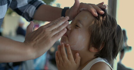 Carefully applying sunscreen to a child's face in slow motion at 800 fps, emphasizing the...
