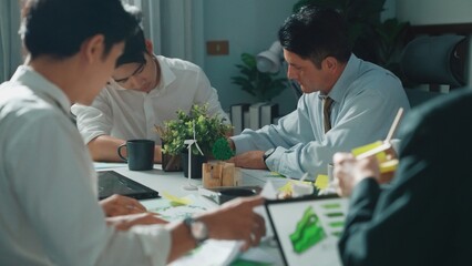 Professional smart business team discussing about using clean energy and sustainable investment at meeting table with wind mill, document with environmental graph and wooden house model. Alimentation.