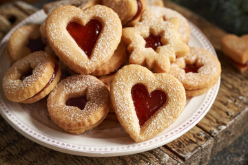 Traditonal Linzer Christmas cookies filled with strawberry marmalade and dusted with sugar on a white plate