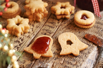 Filling bell shaped Linzer Christmas cookie with strawberry jam, close up