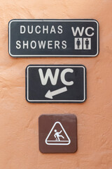 Three rest room signs on a terracotta colored wall