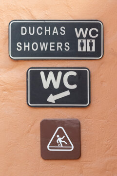 Three rest room signs on a terracotta colored wall