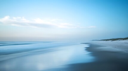 Obraz premium A long exposure photograph of the beach. The ocean is calm and blue, with some fog on top