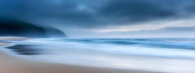 Fototapeta premium A long exposure photograph of the beach. The ocean is calm and blue, with some fog on top