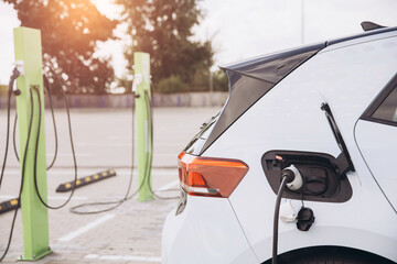 Close-Up of Electric Car Charging at Outdoor Station in Sunny Environment Promoting Sustainable...