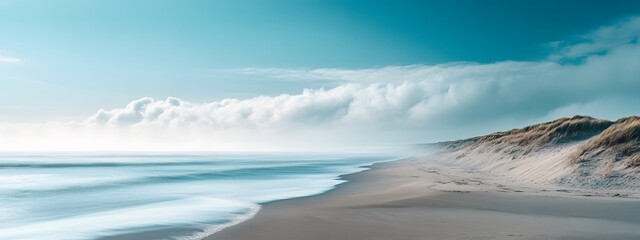 A long exposure photograph of the beach. The ocean is calm and blue, with some fog on top