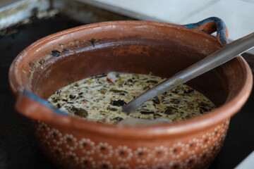 Photography without people of a traditional clay pot, with creamy soup which is an ethnic Mexican...
