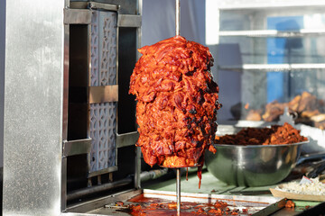Pork al pastor meat, marinated and roasting on a rustic grill, for the preparation of authentic al...