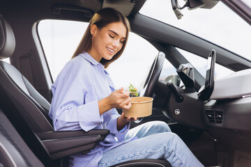 Naklejka premium Young Woman Enjoying Healthy Lunch Inside Her Car, Embracing Convenient On the Go Lifestyle with Nutritious Snack during Busy Day