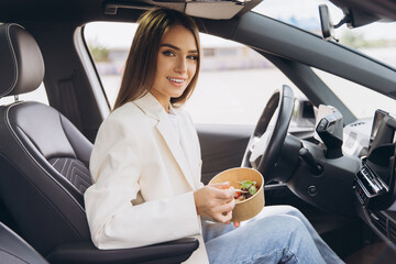 Naklejka premium Young Woman Enjoying Healthy Lunch in Car While Commuting to Work During Busy Weekday