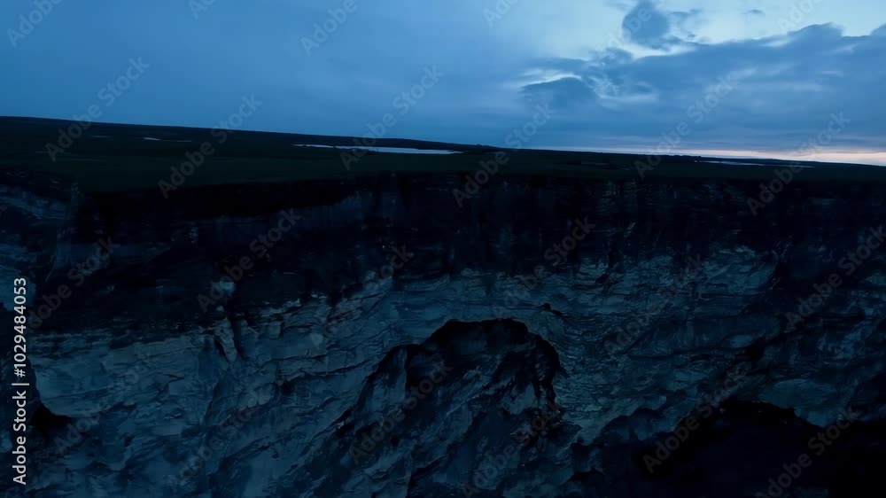 Aufkleber breathtaking view of steep cliffs casting long shadows over a vast grassland at twilight, creating a