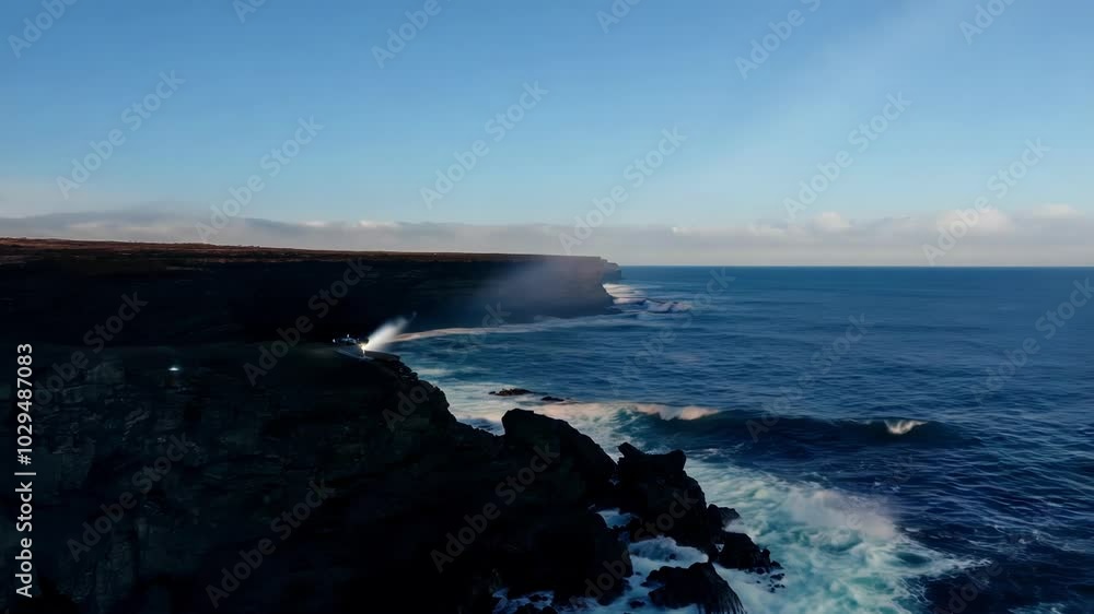 Poster Powerful beam of light is illuminating the ocean waves from a cliff, creating a dramatic contrast against the twilight sky