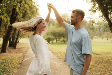 Joyful couple dancing on a sunny day in a picturesque park.