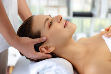 Caucasian woman enjoying relaxing anti-stress head massage and pampering facial beauty skin recreation leisure in dayspa modern light ambient at luxury resort or hotel spa salon. Quiescent